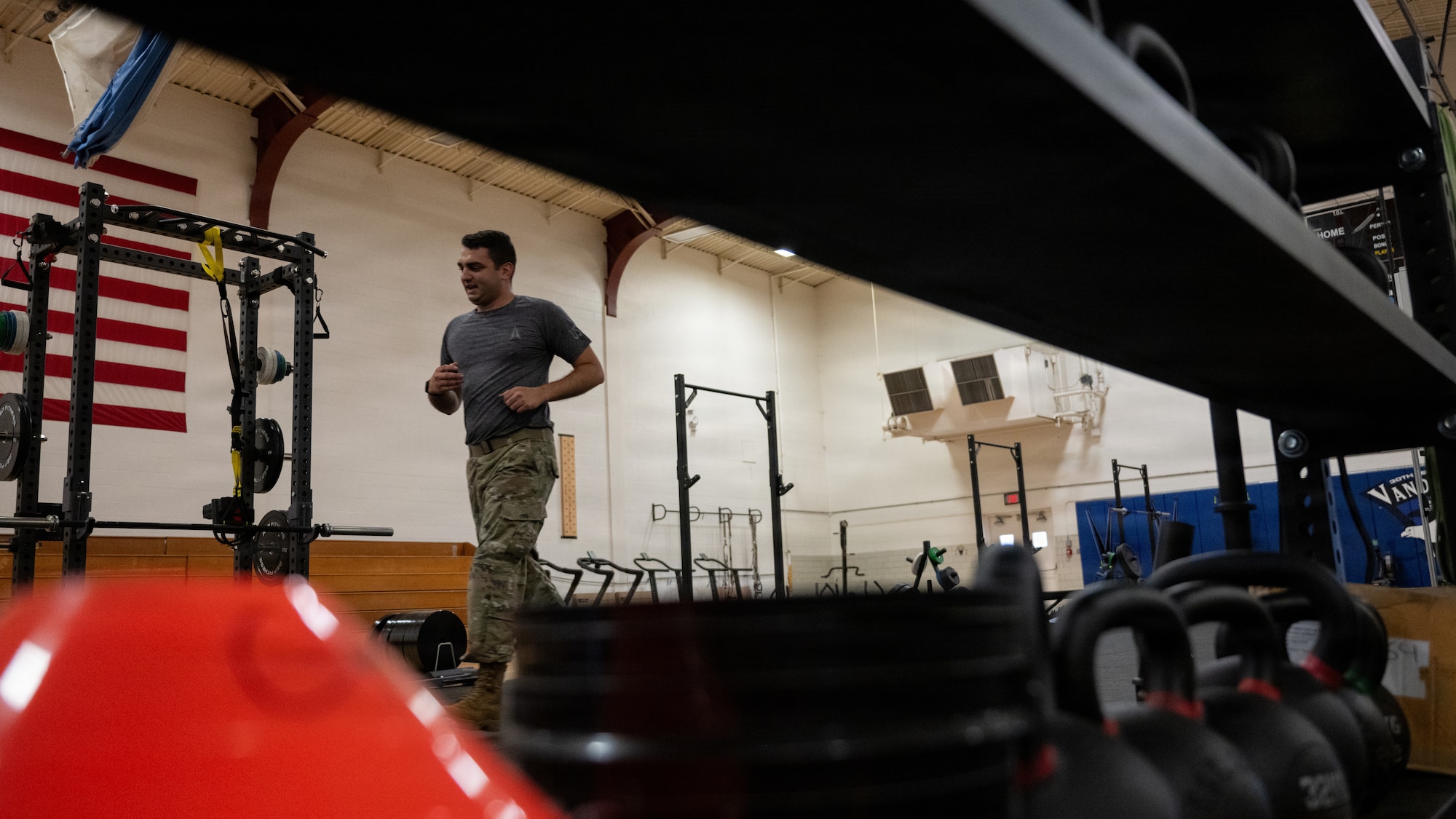 A servicemember does a shuttle run in a gym.