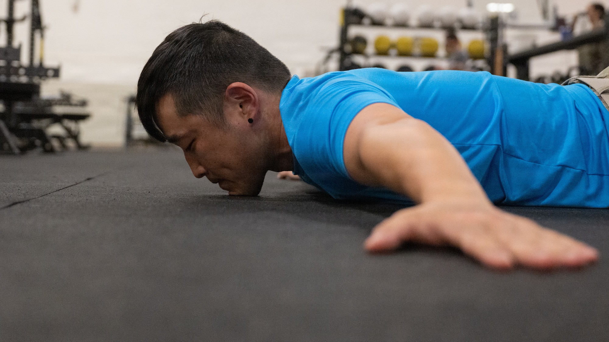 A servicemember does a pushup in a gym.