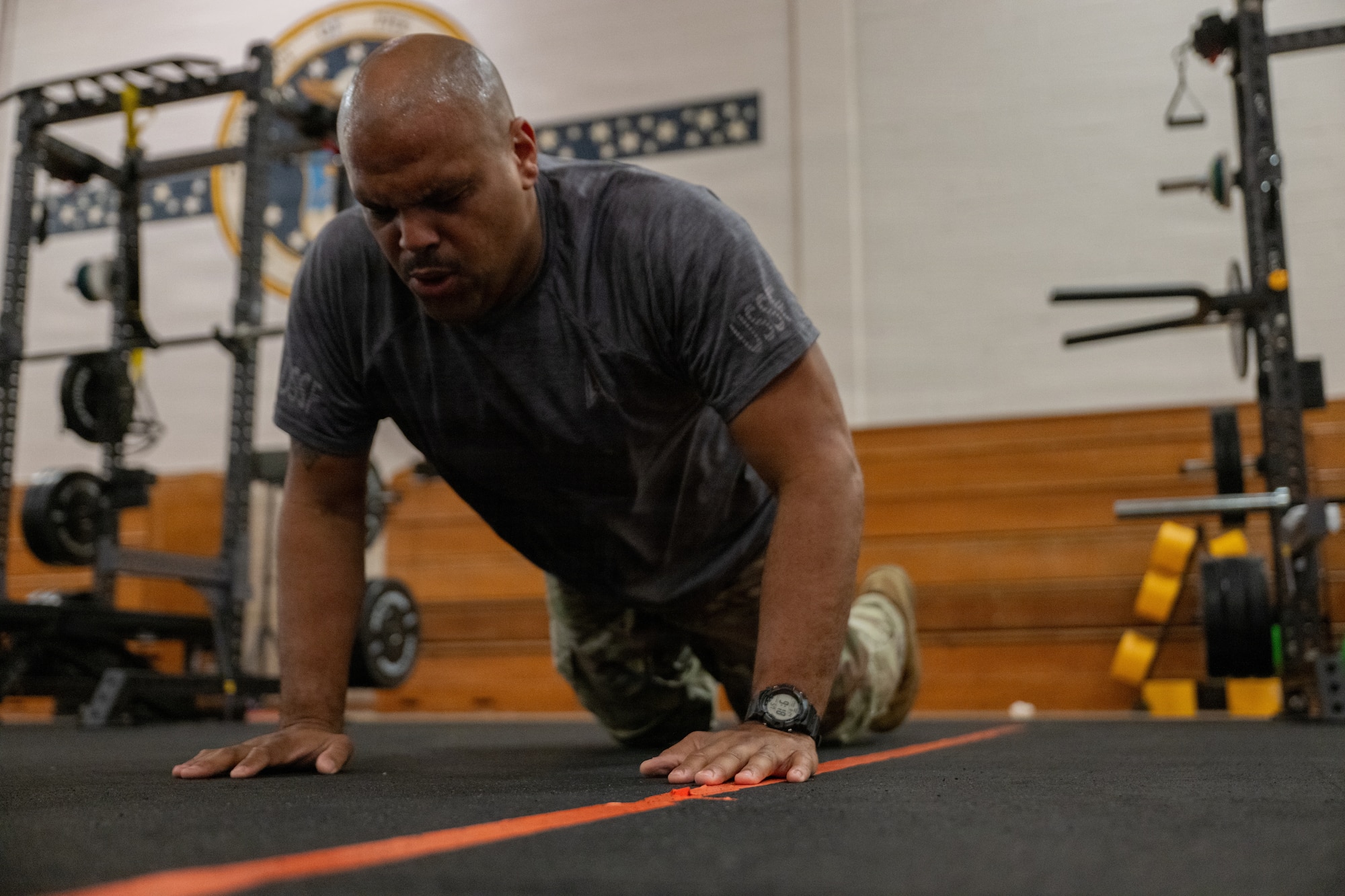 A service member does a push up in a gym.