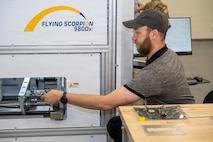 Photo of employee removing a circuit card from a machine.