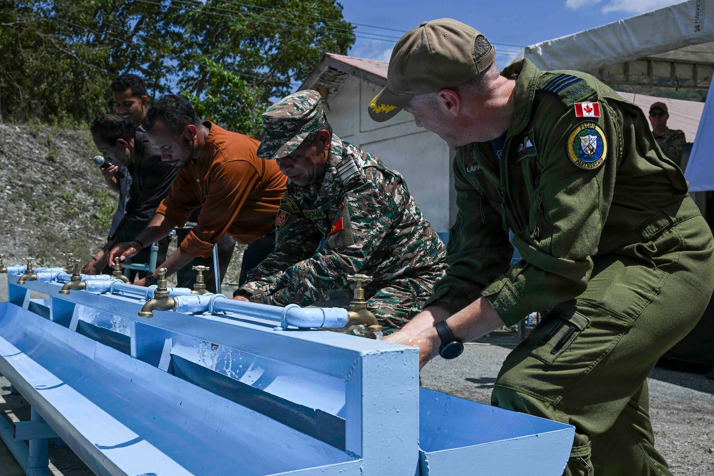 Canadian Armed Forces Col. Alain Lafrenière, right, deputy mission commander of Pacific Partnership 2026 (PP26), uses a newly installed handwashing station alongside members of the Timor-Leste Defence Force (F-FDTL) and Escola Básica Filial (EBF) Kasnafar administrators during a ribbon-cutting ceremony for a PP26 engineering line of effort construction project at EBF Kasnafar in Dili, Timor-Leste, Aug. 24, 2026. During the project, U.S. Navy Seabees assigned to Amphibious Construction Battalion (ACB) 1, alongside engineers from the Timor-Leste Defence Force, renovated an exterior school building and added a new water tank, increasing the school’s capacity to accommodate students and improving its facilities. Now in its 22nd iteration, the Pacific Partnership series is the largest annual multinational humanitarian assistance and disaster management preparedness mission conducted in the region. Pacific Partnership works collaboratively with host and partner nations to enhance regional interoperability and disaster response capabilities, increase security in the region, and foster new and enduring friendships in the Indo-Pacific. (U.S. Navy photo by Mass Communication Specialist 2nd Class T’ara Tripp)