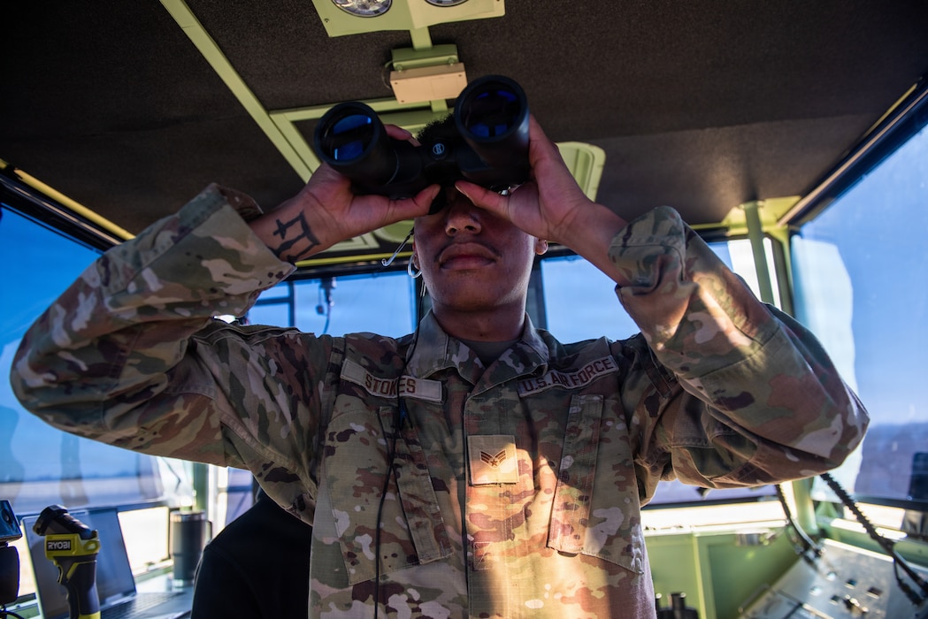Airman looking across an airfield from a mobile control tower