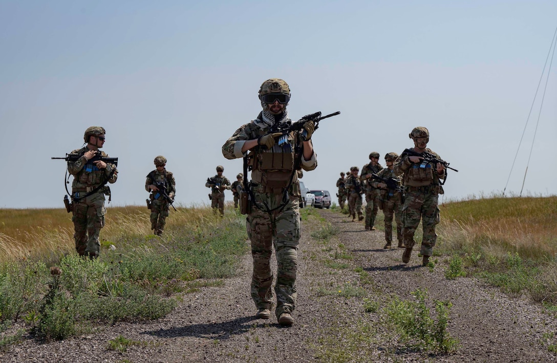 Airmen walk through a field.