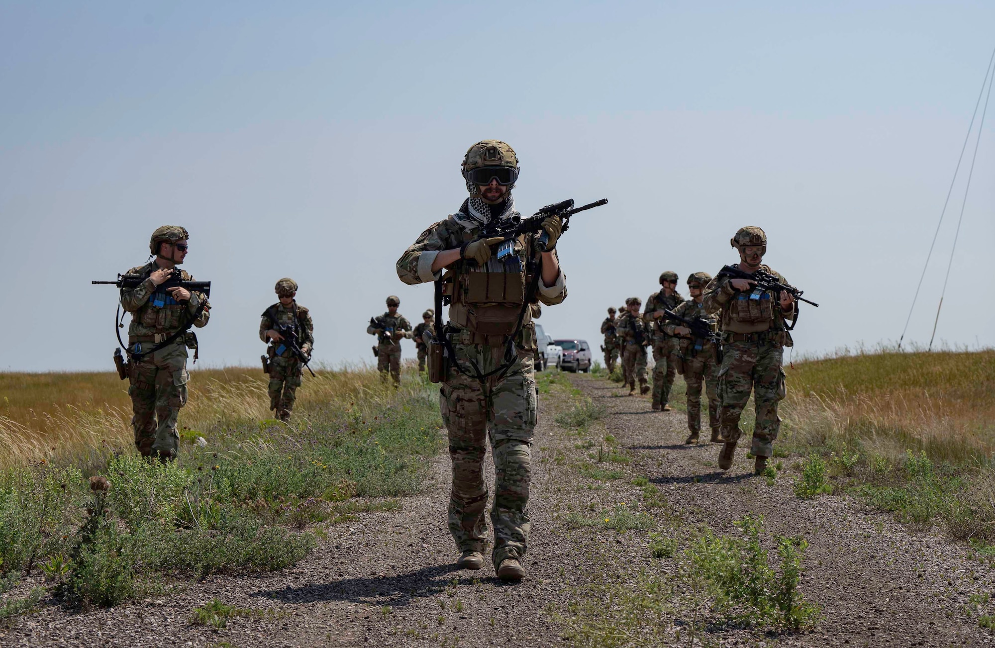 Airmen walk through a field.