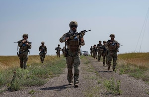 Airmen walk through a field.