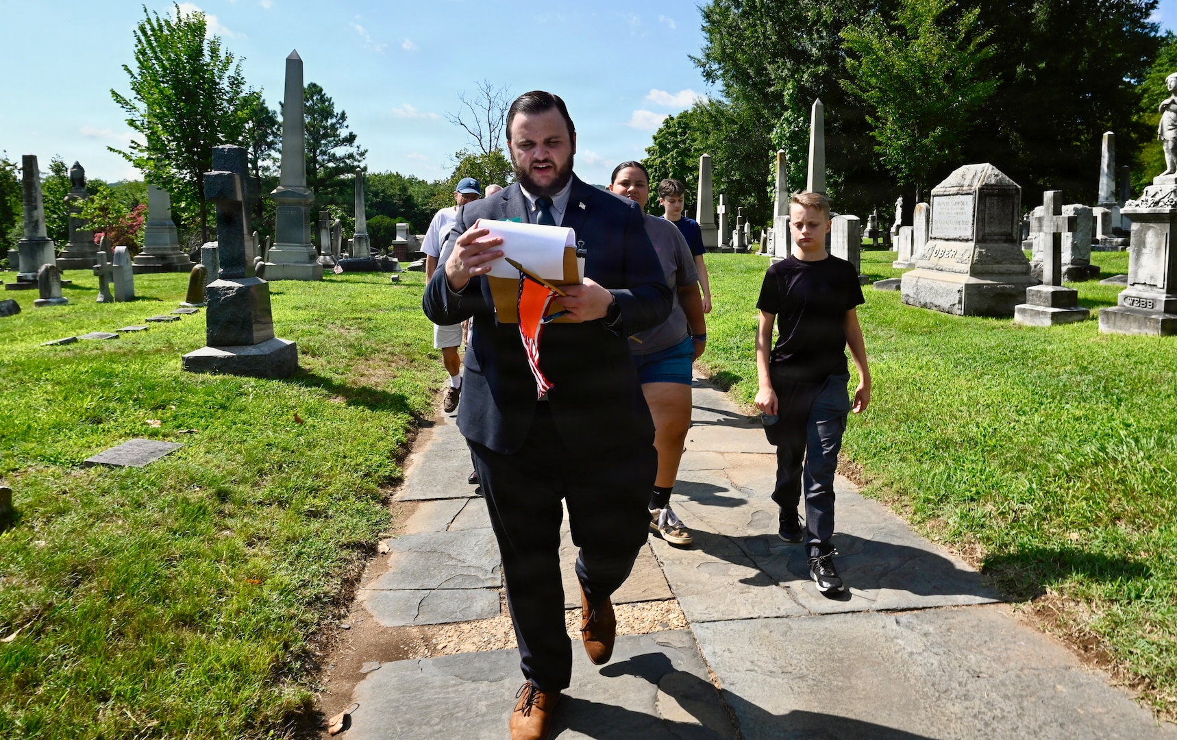 A.J. Orlikoff, Director of Programming at Historic Congressional Cemetery, leads attendees on a guided tour and places a commemorative flag at the final resting place of each identified D.C. Militia member buried at the cemetery in Washington, D.C., Aug. 24, 2026. The tribute honored the Citizen-Soldiers who defended the nation’s capital in 1814 while connecting their legacy of service to the generations who continue that mission today.