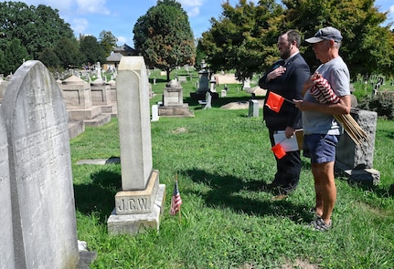 A.J. Orlikoff, Director of Programming at Historic Congressional Cemetery, leads attendees on a guided tour and places a commemorative flag at the final resting place of each identified D.C. Militia member buried at the cemetery in Washington, D.C., Aug. 24, 2026. The tribute honored the Citizen-Soldiers who defended the nation’s capital in 1814 while connecting their legacy of service to the generations who continue that mission today.