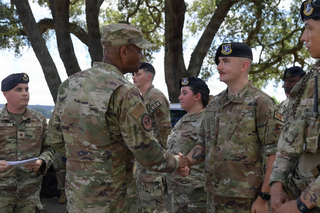 A man wearing a U.S. Air Force uniform shakes hands with a group of Airmen.