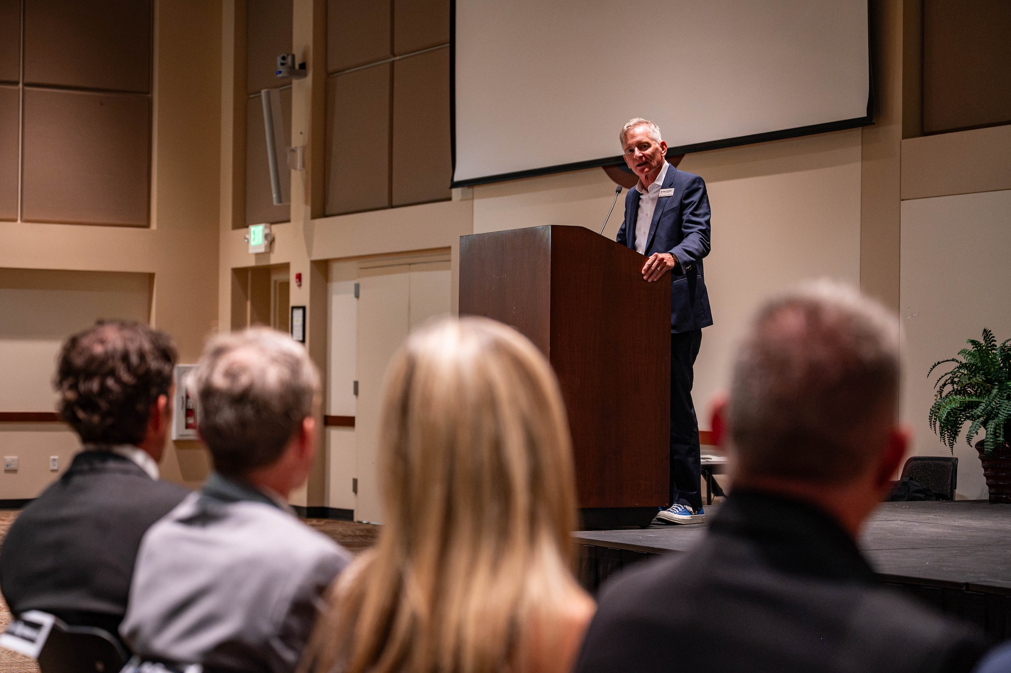 a man in a suit stands at a podium in front of an audience