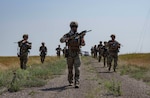 Airmen walk through a field.