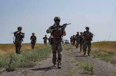 Airmen walk through a field.