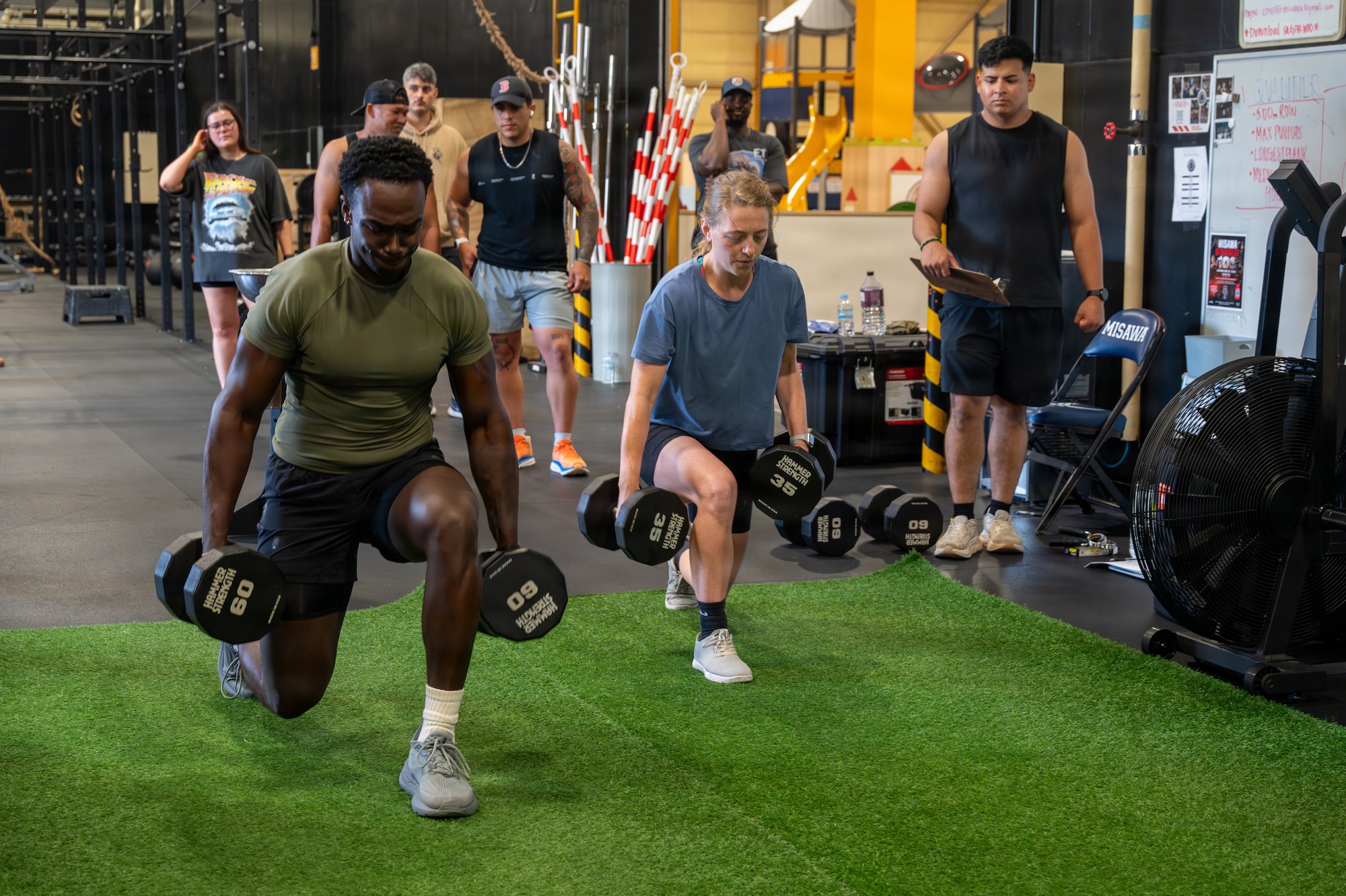U.S. Air Force Airman 1st Class James Coriolan, 35th Security Forces Squadron response force member, and military spouse Samantha Willenbrok perform weighted walking lunges during Misawa’s Strongest 100 competition at Misawa Air Base, Japan, Aug. 22, 2026. The event brought Airmen, families and members of Team Misawa together through friendly competition, strengthening connections that contribute to a supportive and resilient joint and bilateral military community. (U.S. Air Force photo by Airman 1st Class Angelica Winther)