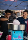 two Airmen in navy blue shirts making cotton candy