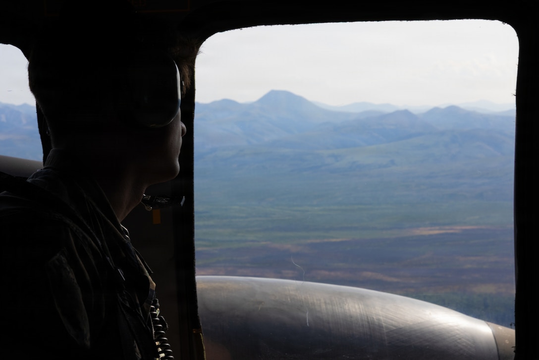 U.S. Marine Corps Lance Cpl. Owen Long, a combat videographer, Headquarters Battalion, Marine Forces Reserve, looks out the window of a Black Hawk helicopter during Operation Arctic Shelter, Fairbanks, Alaska, Aug. 13, 2026. Operation Arctic Shelter is an Innovative Readiness Training mission partnered with the Interior Regional Housing Authority to build affordable housing, providing Marines with critical vertical and horizontal construction training in a cold-weather environment. (U.S. Marine Corps photo by Lance Cpl. Claire Cheney)