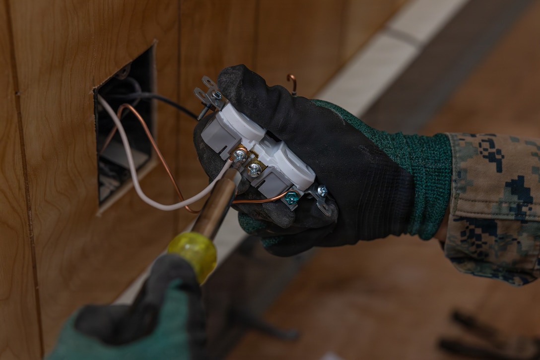 U.S. Marine Corps Sgt. Henry Sanchezzuniga, a team leader with 6th Engineer Support Battalion, Force Headquarters Group, Marine Forces Reserve, fixes an outlet during Operation Arctic Shelter, Beaver, Alaska, Aug. 13, 2026. Operation Arctic Shelter is an Innovative Readiness Training mission partnered with the Interior Regional Housing Authority to build affordable housing, providing Marines with critical vertical and horizontal construction training in a cold-weather environment. (U.S. Marine Corps photo by Lance Cpl. Claire Cheney)