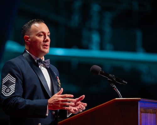 A man if formal dress uniform gestures while speaking at a podium.