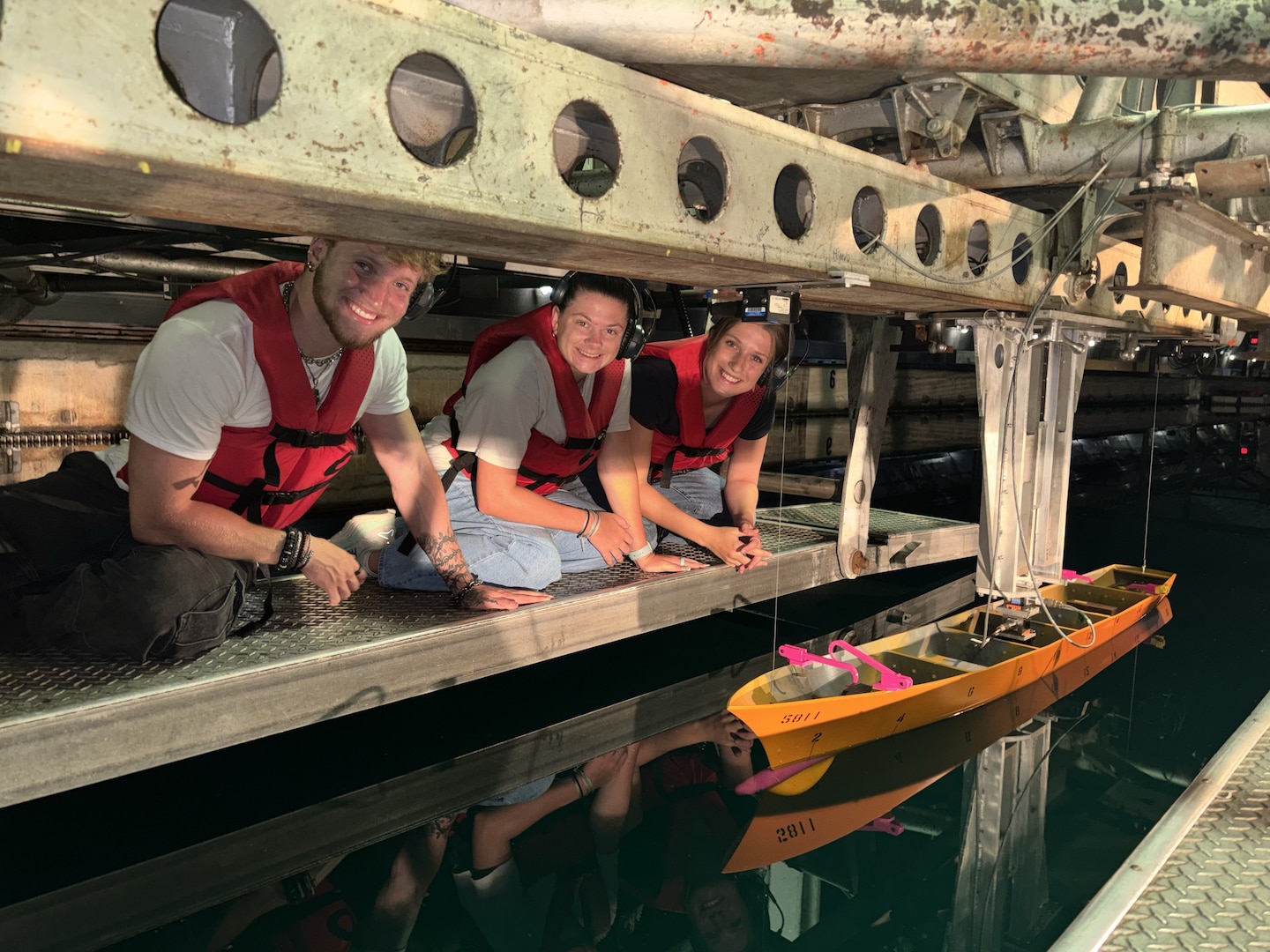 Collin Morr, left, Brianna Ellis and Zoey Shepard observe their senior capstone model in the David Taylor Model Basin at Naval Surface Warfare Center, Carderock Division in West Bethesda, Maryland. Through the STEM Student Employment Program (SSEP), the Florida Institute of Technology students designed, fabricated and tested the model while working alongside Carderock engineers.