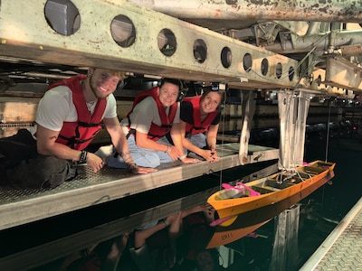 Collin Morr, left, Brianna Ellis and Zoey Shepard observe their senior capstone model in the David Taylor Model Basin at Naval Surface Warfare Center, Carderock Division in West Bethesda, Maryland. Through the STEM Student Employment Program (SSEP), the Florida Institute of Technology students designed, fabricated and tested the model while working alongside Carderock engineers.