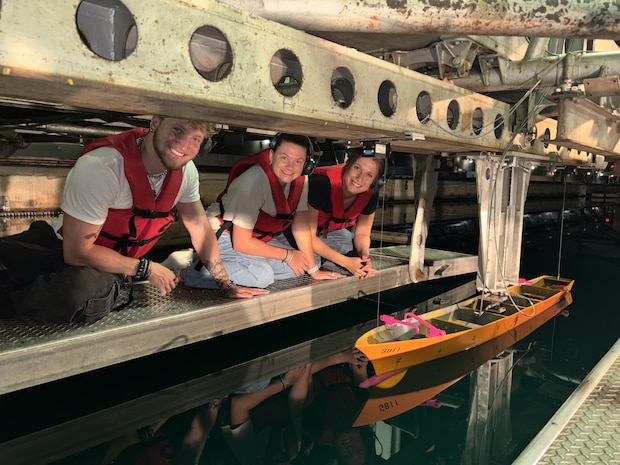Collin Morr, left, Brianna Ellis and Zoey Shepard observe their senior capstone model in the David Taylor Model Basin at Naval Surface Warfare Center, Carderock Division in West Bethesda, Maryland. Through the STEM Student Employment Program (SSEP), the Florida Institute of Technology students designed, fabricated and tested the model while working alongside Carderock engineers.