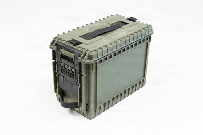 A large ammo can is on the floor in a room.