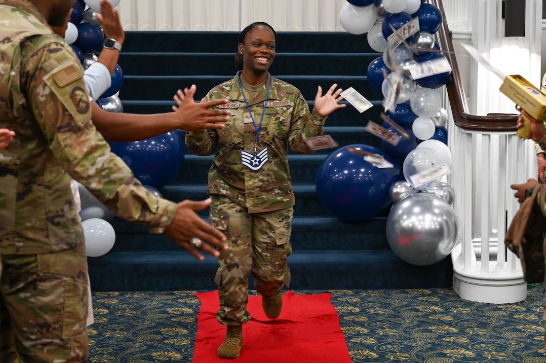 U.S. Air Force Senior Airman Shakiba Ausbrooks, travel team lead for the 11th Comptroller Squadron, high-fives attendees during the staff sergeant release party.