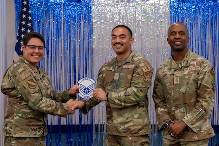 U.S. Air Force Senior Airman Andrew Dagami, center, budget analyst for the 11th Comptroller Squadron, receives a memento from Col. Rebecca Corbin, left, deputy commander of Joint Base Anacostia-Bolling and the 11th Wing, and Chief Master Sgt. Anthony Thompson Jr., senior enlisted leader for JBAB and 11th Wing command chief.