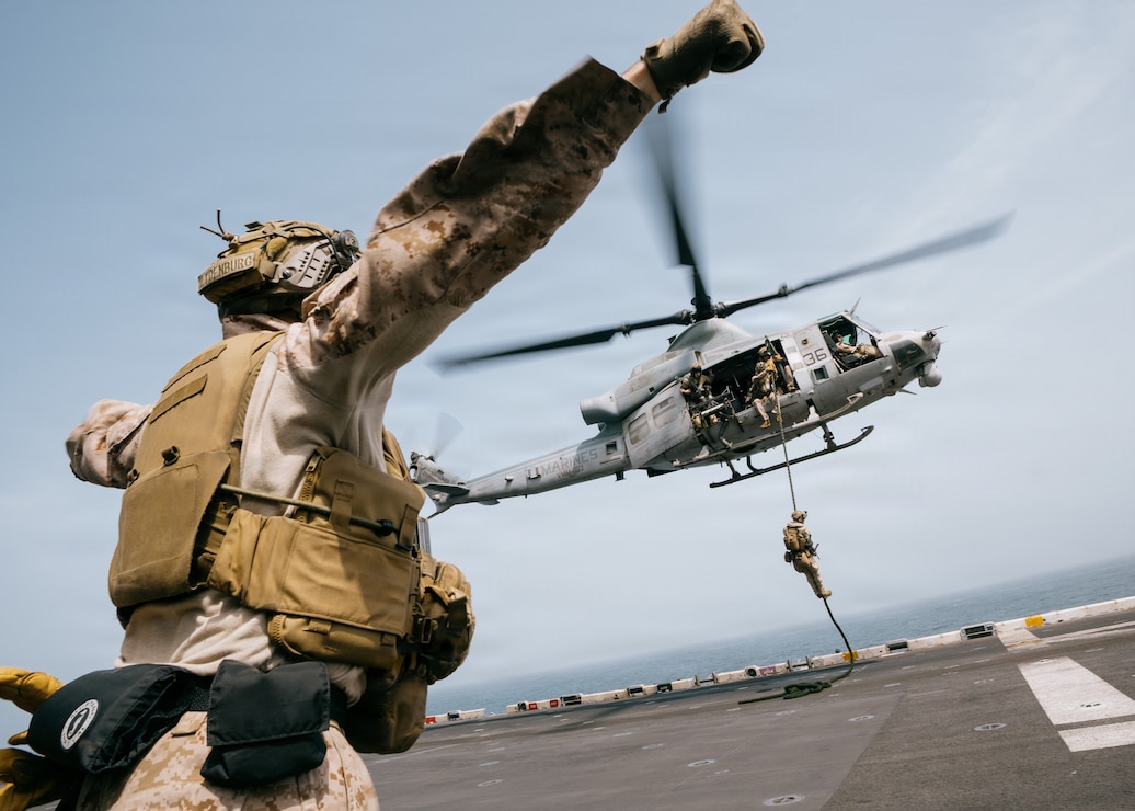 A U.S. Marine with Battalion Landing Team 3/5, 11th Marine Expeditionary Unit, fast-ropes from a UH-1Y Venom assigned to Marine Medium Tiltrotor Squadron (VMM) 163 (Reinforced), 11th MEU, on the flight deck of Wasp-class amphibious assault ship USS Boxer (LHD 4) in the U.S. Central Command area of responsibility, Aug. 15, 2026. (U.S. Marine Corps photo by Sgt. Joseph Helms)