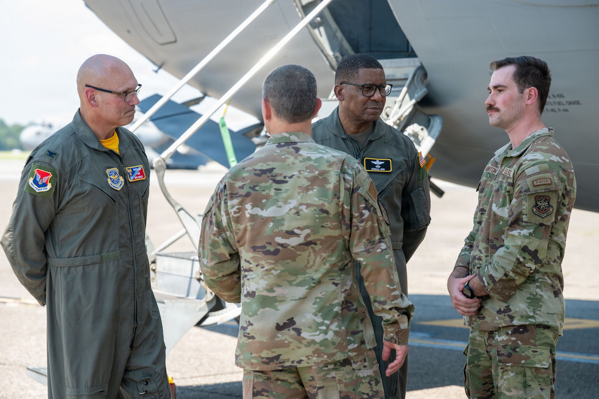 Four people stand in a group in front of an aircraft.