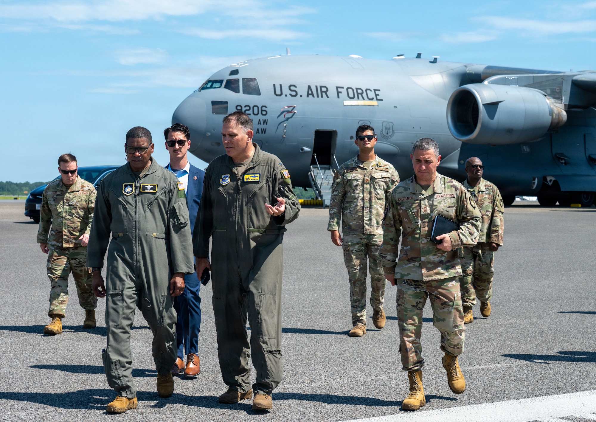 Seven people in various uniforms walk away from a C-17 Globemaster III on the flightline.