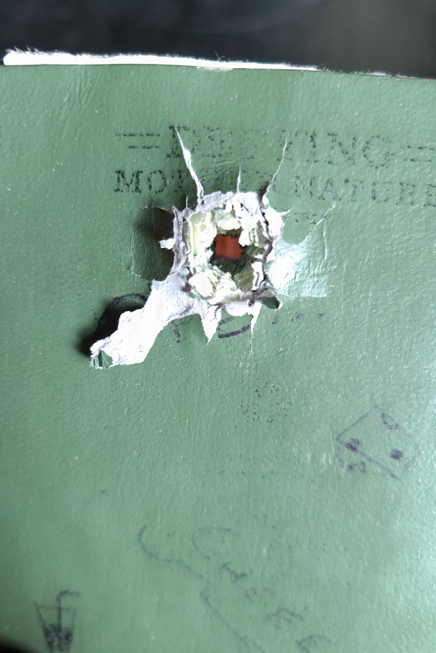 A tiny piece of exploded metal shrapnel sits on a military notebook.