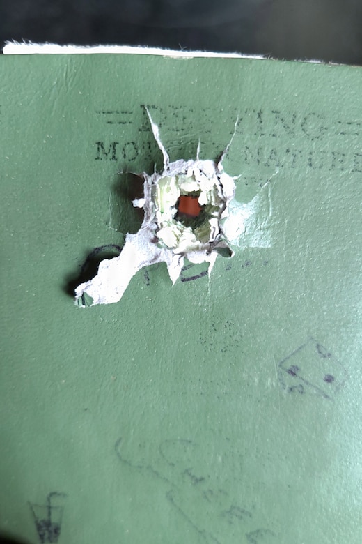 A tiny piece of exploded metal shrapnel sits on a military notebook.