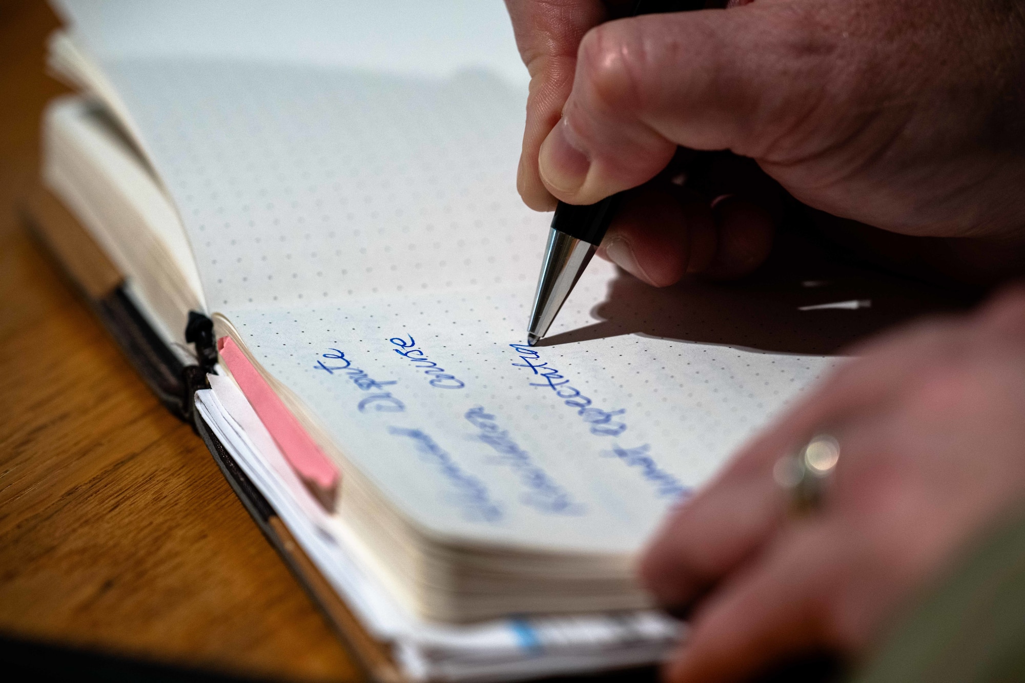 close shop of hands writing in the notebook with blue writing