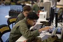 U.S. Marine Corps Cpl. Victor Deverney, left, and Lance Cpl. Maximillian Sadchikov, both with the Chemical Biological Incident Response Force (CBIRF), monitor communication systems during the Freedom 250 Grand Prix in Washington, D.C., Aug. 23, 2026. CBIRF enhanced its operational readiness to support contingency operations during the high-visibility event.  (DoW photo by Prentice Colter)