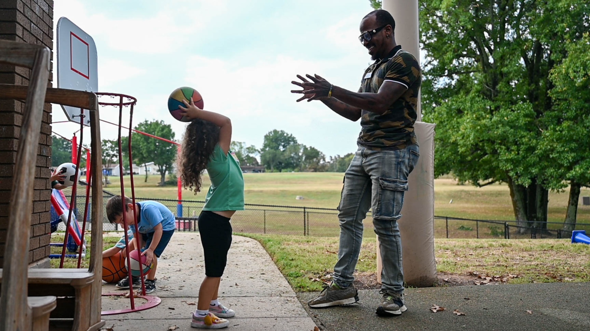 A man holds out his hands while a child throws him a ball.