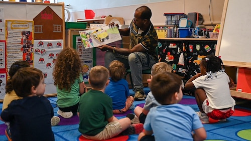 A man read a book to a group of children.