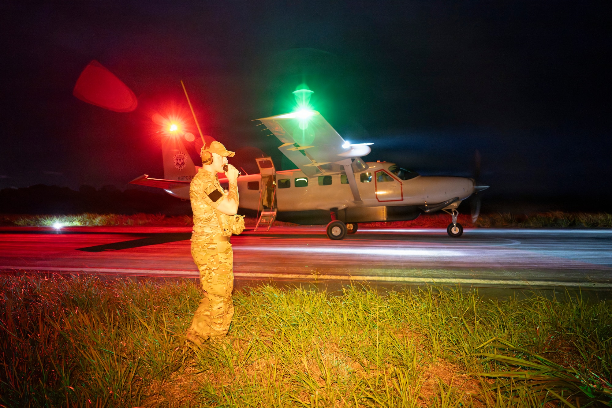 Man speaks on radio while plane taxis behind at night.