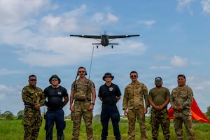 Men stand for a photo as a plane flies overhead.