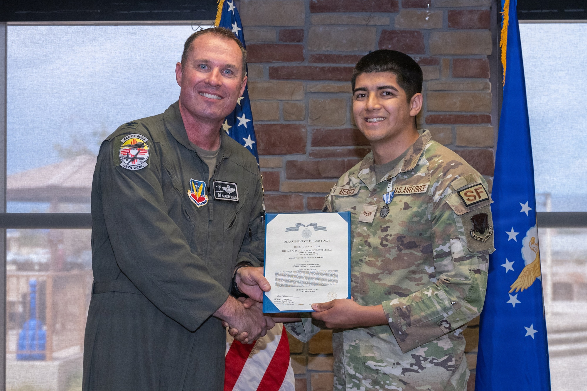 U.S. Air Force Senior Airman Michael Atengco, 49th Security Forces Squadron visitor control center clerk, right, receives the Air and Space Achievement Medal with Combat Device during the 49th Wing Security Forces Decoration Ceremony at Holloman Air Force Base, New Mexico, July 10, 2026. While deployed, Atengco supported operations in the U.S. Central Command area of responsibility. (U.S. Air Force photo by Airman 1st Class Elijah Strickland)