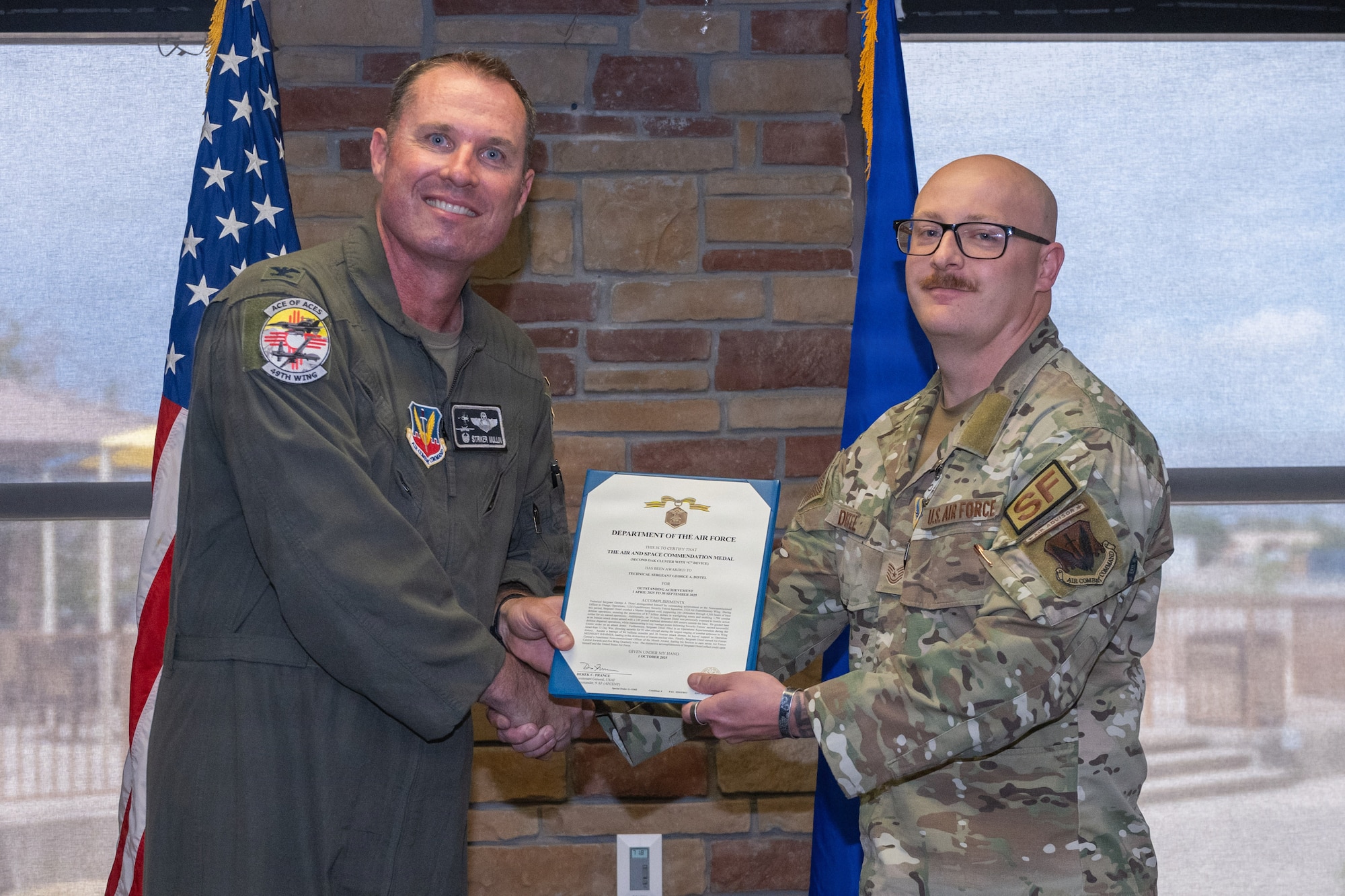 U.S. Air Force Tech. Sgt. George Distel, 49th Security Forces Squadron superintendent of plans and programs, right, receives the Air and Space Commendation Medal with Second Oak Leaf Cluster and Combat Device during the 49th Wing Security Forces Decoration Ceremony at Holloman Air Force Base, New Mexico, July 10, 2026. While deployed, Distel supported operations in the U.S. Central Command area of responsibility. (U.S. Air Force photo by Airman 1st Class Elijah Strickland)