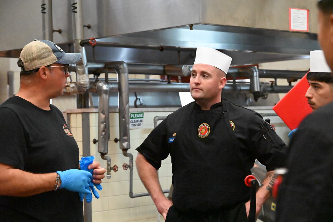 (Left to Right) Bob Trudnak celebrity pit master speaks to food service Marines assigned to Combined Arms Training Center, Camp Fuji, Cpl. William Grant and Lance Cpl. Eric Gutierrez at a barbecue class offered during the Marine Corps Installations Pacific Food Services Specialist of the Quarter competition, August 18, 2026. (U.S. Marine Corps photo by Song Jordan)