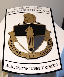 A plaque bearing the U.S. Army John F. Kennedy Special Warfare Center and School crest sits on a table during a ceremony at the John F. Kennedy Presidential Library and Museum in Boston, April 16, 2019.