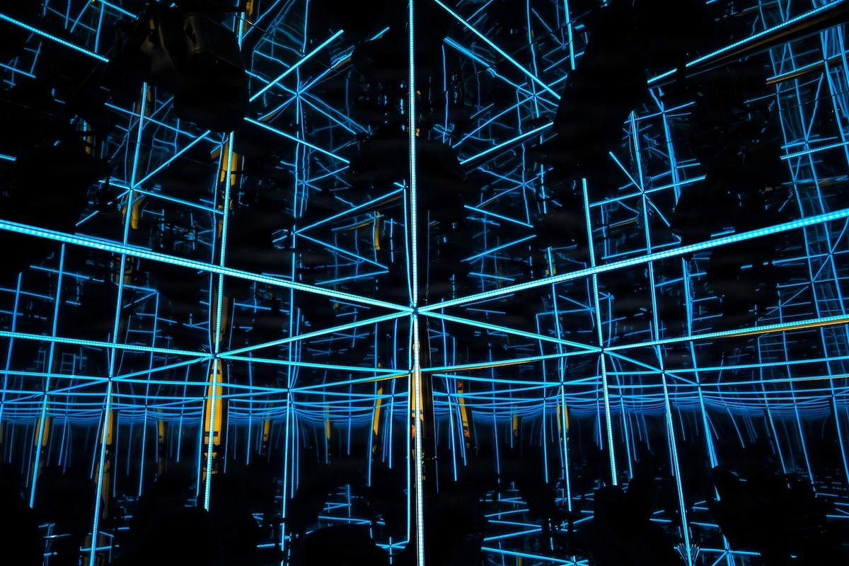 A dark mirrored room is covered in light strips.