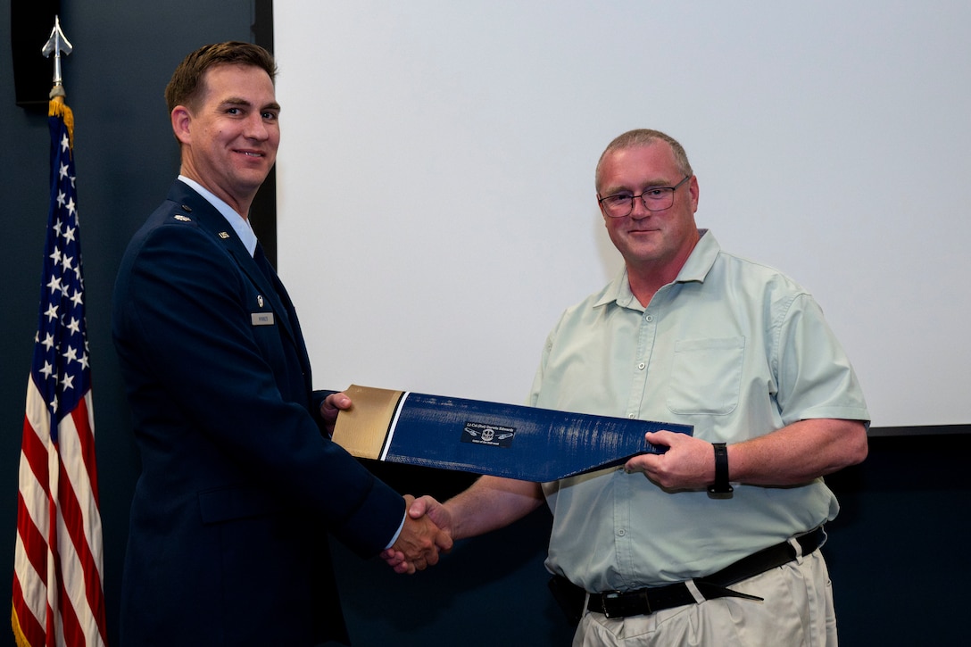 Two people exchanging an award.