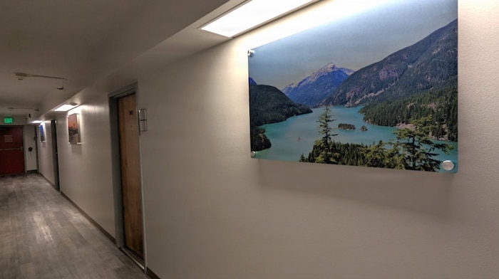 A photo of a renovated hallway in an Unaccompanied Housing (UH) building – commonly known as barracks – on Naval Base Kitsap-Bremerton. The 10-story, 152-room barracks received full-scale interior renovation and new furnishing following fire and water damage sustained in August 2025. The milestone marks the first of the Navy’s six major sustainment, restoration, and modernization projects funded through the Barracks Task Force to reach completion, directly advancing the Navy’s “No Sailor Living Afloat” initiative – a drive to move Sailors off docked ships and into high-quality shore housing – and the Commander, Navy Installations Command (CNIC) Quality of Service improvement efforts.