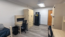 A photo of a renovated room in an Unaccompanied Housing (UH) building – commonly known as barracks – on Naval Base Kitsap-Bremerton. The 10-story, 152-room barracks received full-scale interior renovation and new furnishing following fire and water damage sustained in August 2025. The milestone marks the first of the Navy’s six major sustainment, restoration, and modernization projects funded through the Barracks Task Force to reach completion, directly advancing the Navy’s “No Sailor Living Afloat” initiative – a drive to move Sailors off docked ships and into high-quality shore housing – and the Commander, Navy Installations Command (CNIC) Quality of Service improvement efforts.