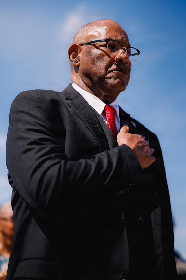 Mr. Russell Woody, deputy for G-3/5 at Marine Corps Installations West, Marine Corps Base Camp Pendleton, stands for the National Anthem during the Civilian Awards Ceremony at MCB Camp Pendleton, Calif., June 11, 2026. The recognition honors Woody's more than 50 years of combined military and federal service, including 31 years as an active-duty Marine and over two decades as a civilian leader supporting Marines, families and mission readiness at Marine Corps Installations West. (U.S. Marine Corps photo by Sgt. Haley Fourmet Gustavsen)