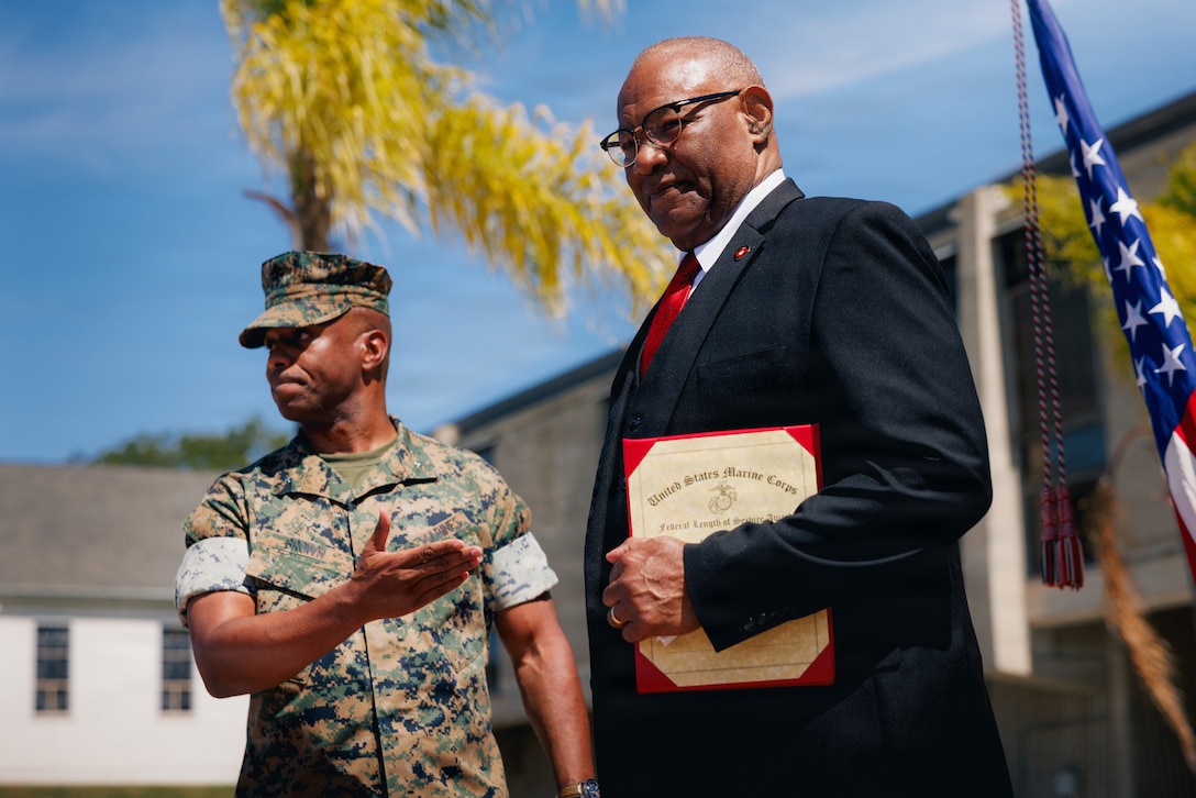 U.S. Marine Corps Brig. Gen. Nick I. Brown, left, commanding general of Marine Corps Installations West, Marine Corps Base Camp Pendleton, delivers the Federal Length of Service Award to Mr. Russell Woody, deputy for G-3/5 at MCIWEST, MCB Camp Pendleton, during the Civilian Awards Ceremony at MCB Camp Pendleton, Calif., June 11, 2026. The recognition honors Woody's more than 50 years of combined military and federal service, including 31 years as an active-duty Marine and over two decades as a civilian leader supporting Marines, families and mission readiness at Marine Corps Installations West. (U.S. Marine Corps photo by Sgt. Haley Fourmet Gustavsen)