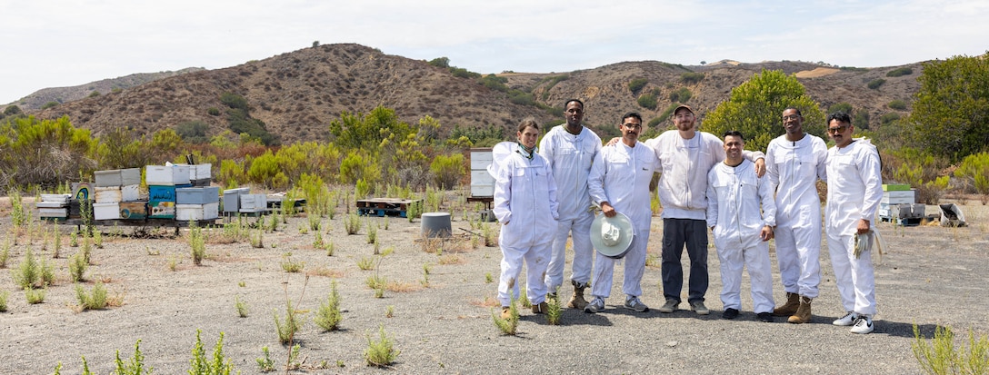 U.S. servicemembers and Colby Gibbs, beekeeper with Bee Leaf USA, pose for a group photo during a beekeeping program meeting at Marine Corps Base Camp Pendleton, California, July 13, 2026. The beekeeper program teaches service members about the ins and outs of beekeeping, the teamwork required in a hive, and the calming effects of the hive’s vibrations and scents. (U.S. Marine Corps photo by Cpl. Jacqueline Akamelu)