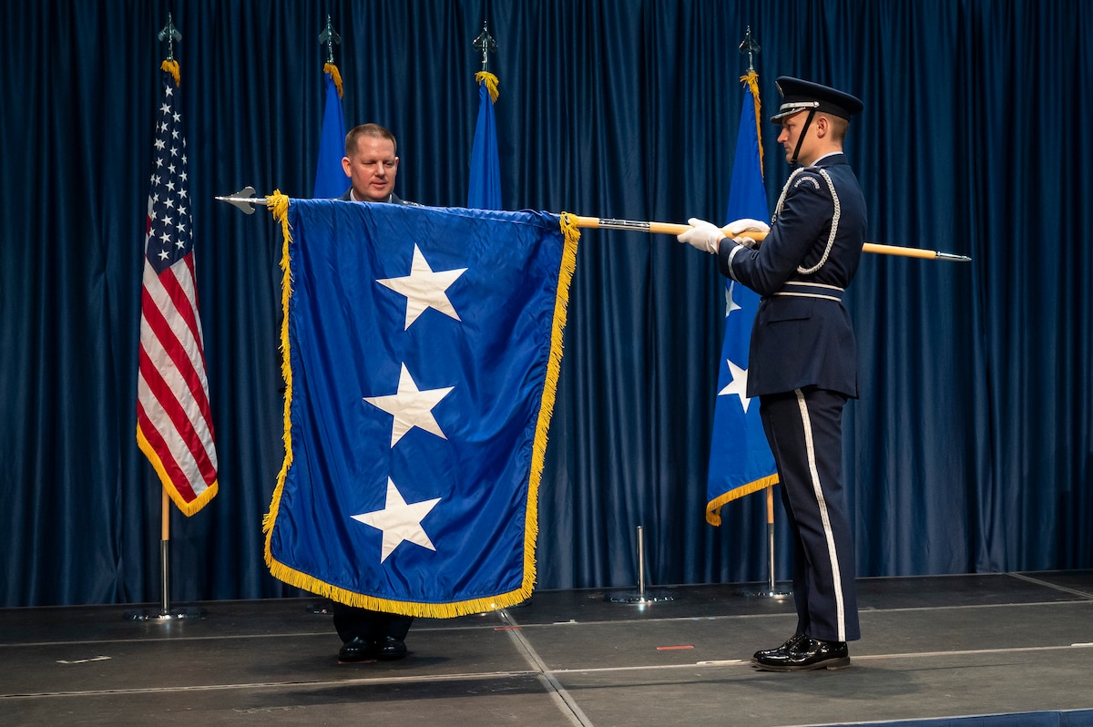 Air Force airman unfurls 3 star flag.