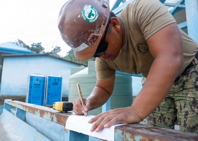 U.S. Navy Utilitiesman 3rd Class Marces Butac, assigned to Amphibious Construction Battalion (ACB) 1, marks sections of a handwashing station as part of a Pacific Partnership 2026 (PP26) engineering project at the Escola Básica Filial Kasnafar schoolhouse, in Dili, Timor-Leste, Aug. 13, 2026.